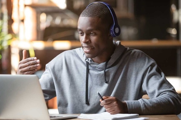 African American man in headphones making video call in cafe